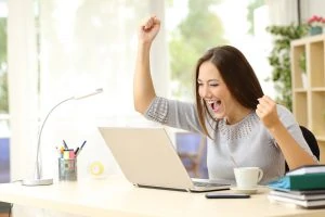 woman cheering in front of a laptop